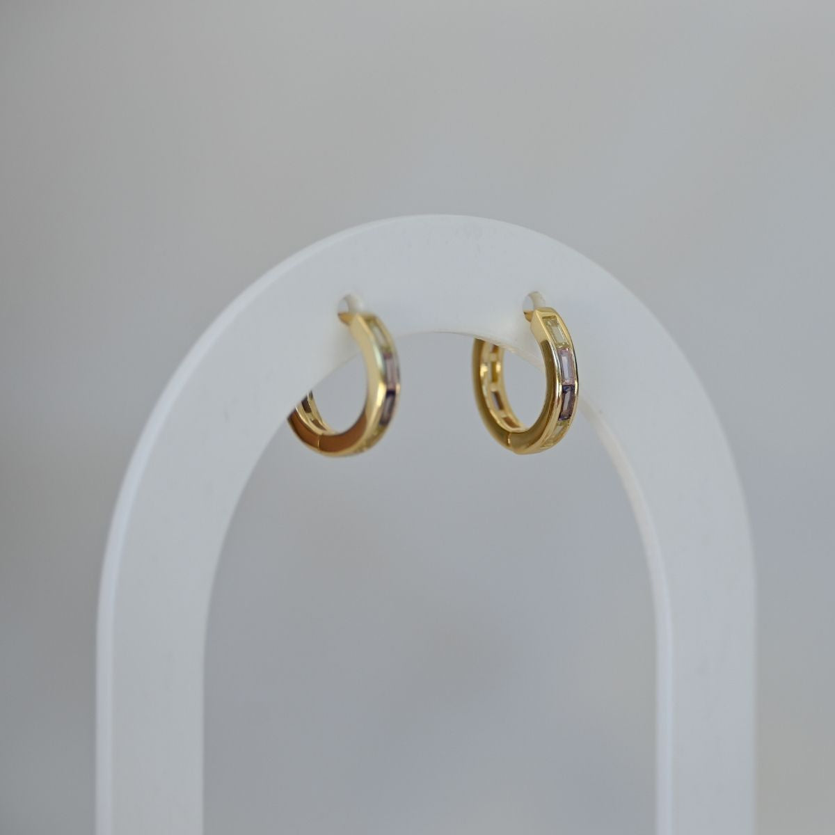 Gold hoop earrings on a white arch