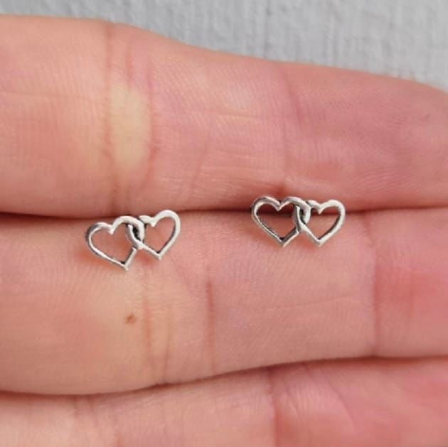 Silver heart-shaped earrings on a hand