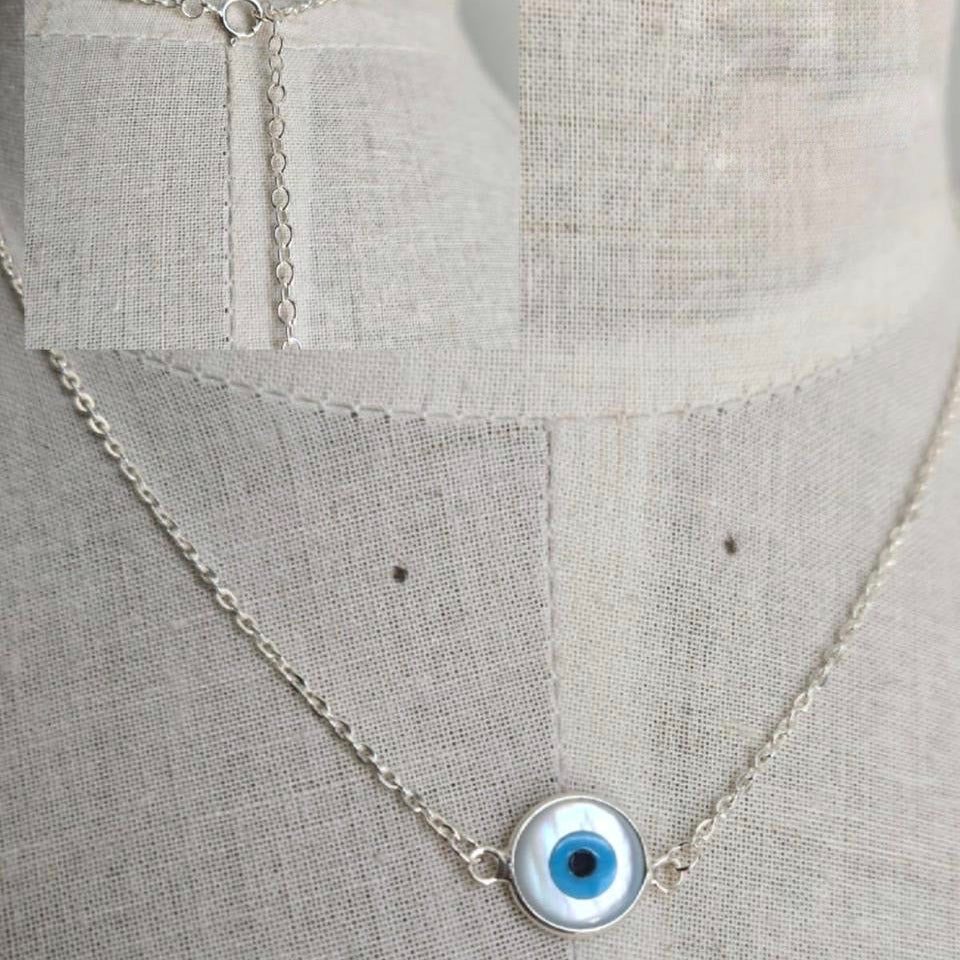 Necklace with a blue eye pendant on a light gray fabric background