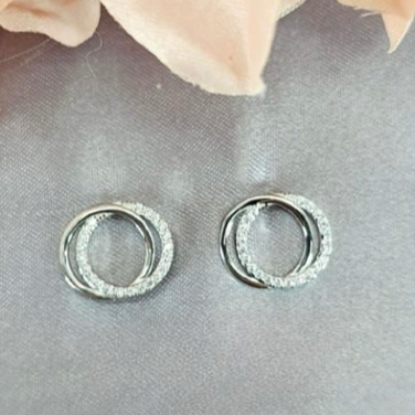 A pair of sterling silver double circle stud earrings with cubic zirconia inlays, displayed against a grey background with a floral pattern.