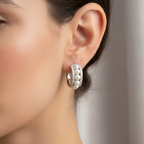 A pair of sterling silver huggies with a cascade of freshwater pearls, displayed on a textured surface.