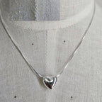 Silver necklace with a heart pendant on a mannequin.