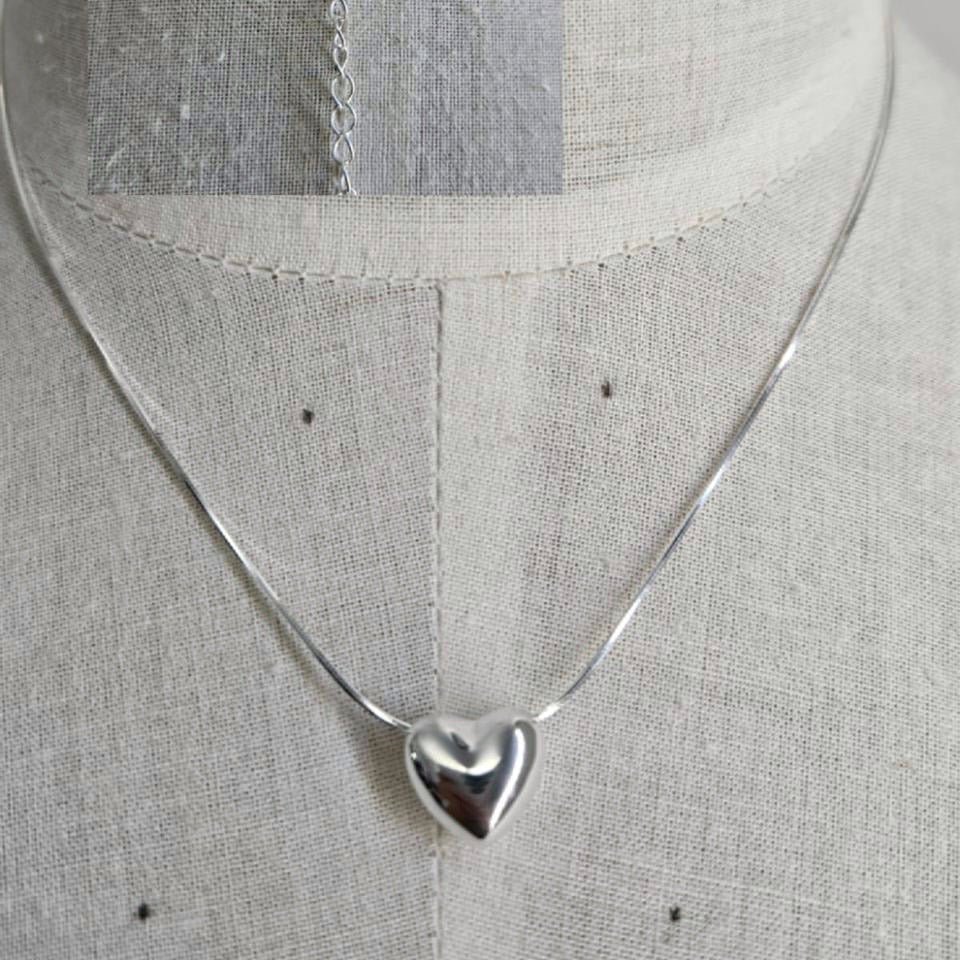 Silver necklace with a heart pendant on a mannequin.