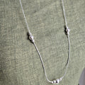 Silver necklace on a green fabric background