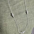 Silver necklace on a green fabric background