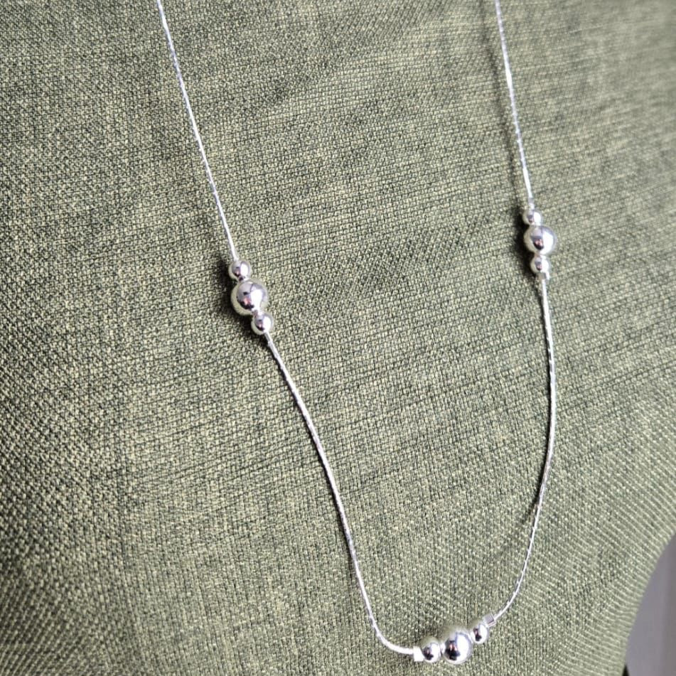 Silver necklace on a green fabric background