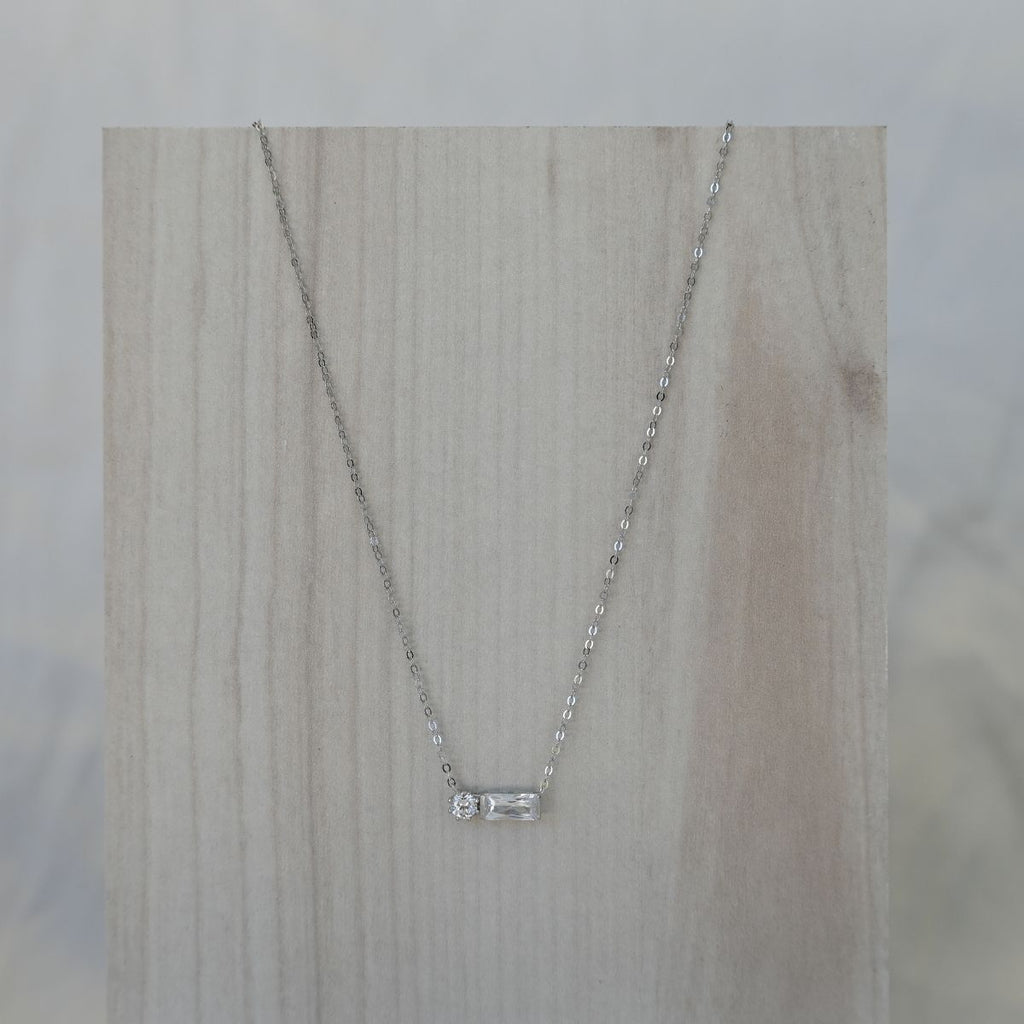 Silver necklace with a small pendant on a wooden surface