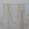 Silver necklace with a small pendant on a wooden surface