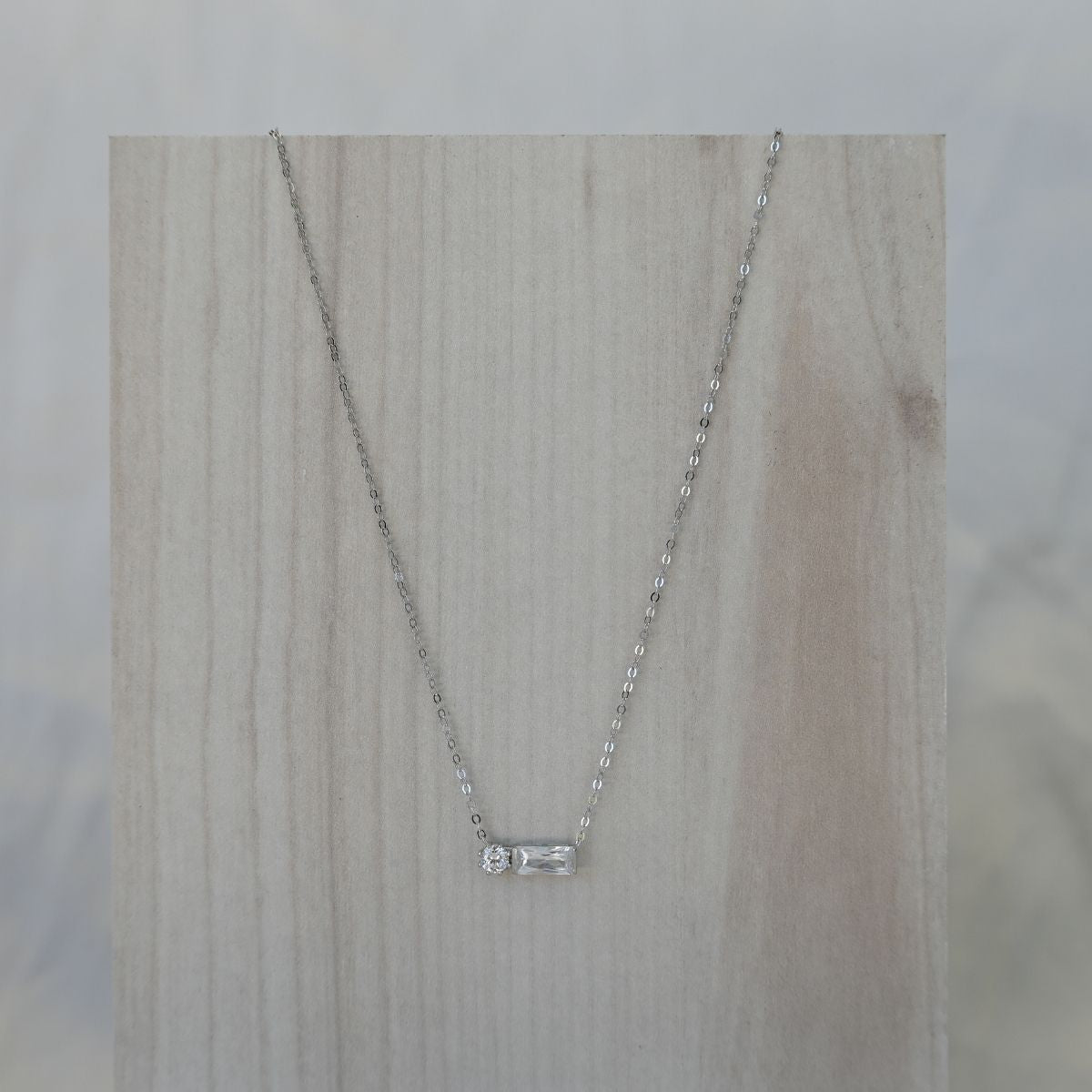 Silver necklace with a small pendant on a wooden surface