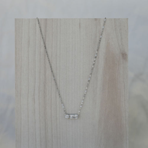 Silver necklace with a small pendant on a wooden surface