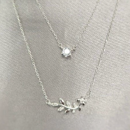 A double layer sterling silver necklace with one layer featuring leaf designs and the other layer showcasing a single cubic zirconia pendant.