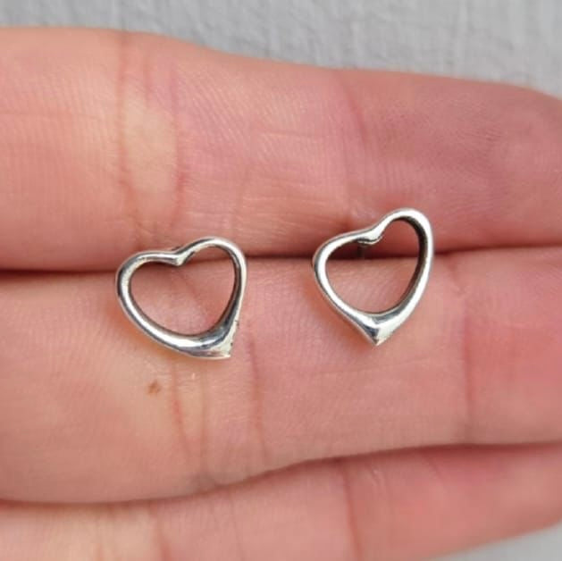 Silver heart-shaped earrings on a hand
