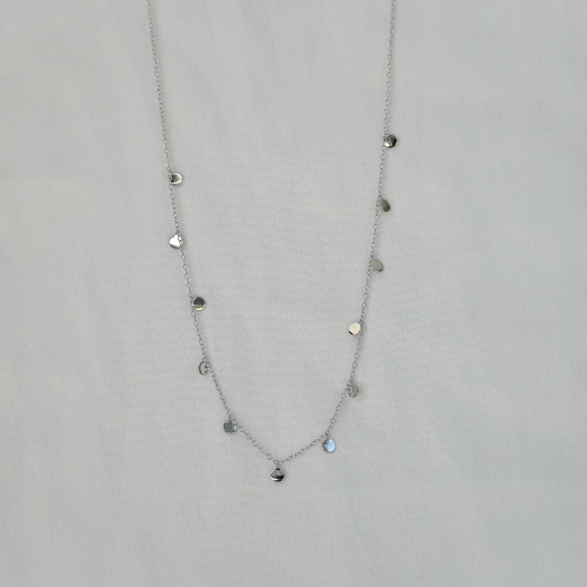 Silver necklace with heart-shaped pendants on a light gray background