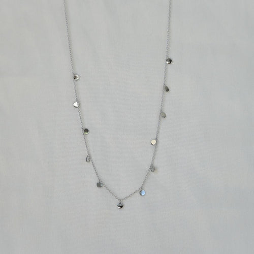 Silver necklace with heart-shaped pendants on a light gray background