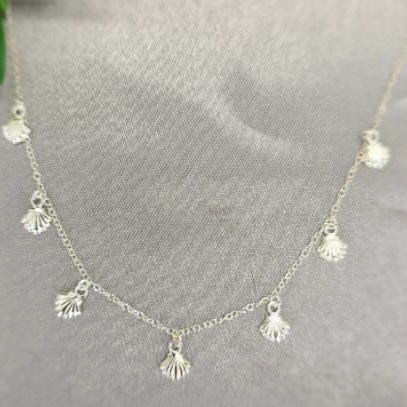 A sterling silver necklace with multiple small, dangling sea shell pendants displayed against a grey background.