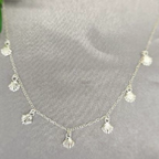 A sterling silver necklace with multiple small, dangling sea shell pendants displayed against a grey background.