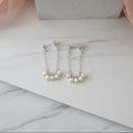 Silver earrings with pearls on a white surface