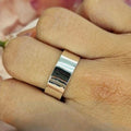 An 8mm sterling silver band ring displayed on a person's finger.