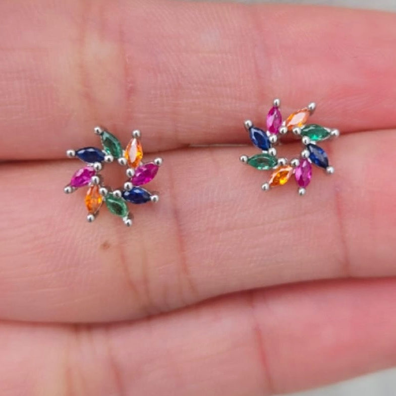 Colorful gemstone earrings on a person's hand
