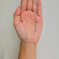 A sterling silver necklace with rainbow-colored dots held in a person's hand.