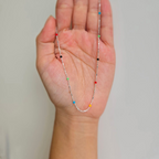 A sterling silver necklace with rainbow-colored dots held in a person's hand.