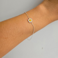 A sterling silver bracelet with a single daisy charm on a person's wrist.