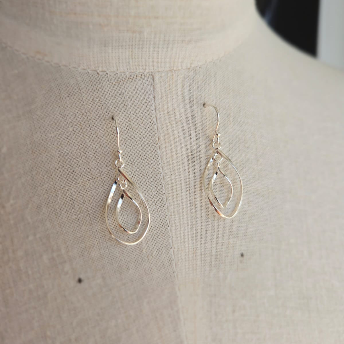 Silver teardrop earrings on a mannequin bust.