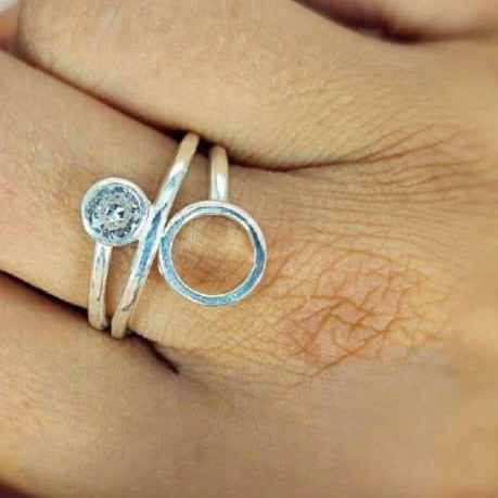 A sterling silver double circle ring with a central cubic zirconia, held on a person's finger.