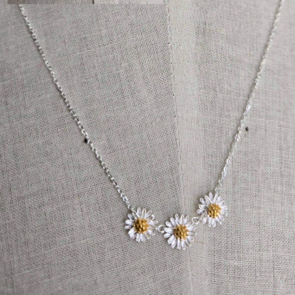 Necklace with daisy pendants on a gray fabric background