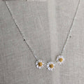 Necklace with daisy pendants on a gray fabric background
