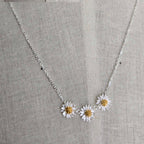 Necklace with daisy pendants on a gray fabric background