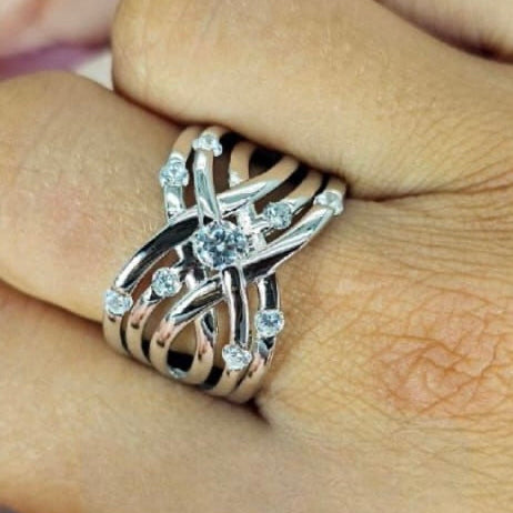 A sterling silver crisscross statement ring with cubic zirconia drops, worn on a person's hand.