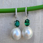 Pearl earrings with green gemstones on a gray background