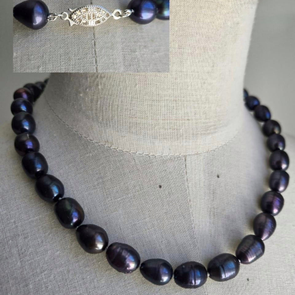 Necklace with dark pearls on a mannequin bust against a neutral background