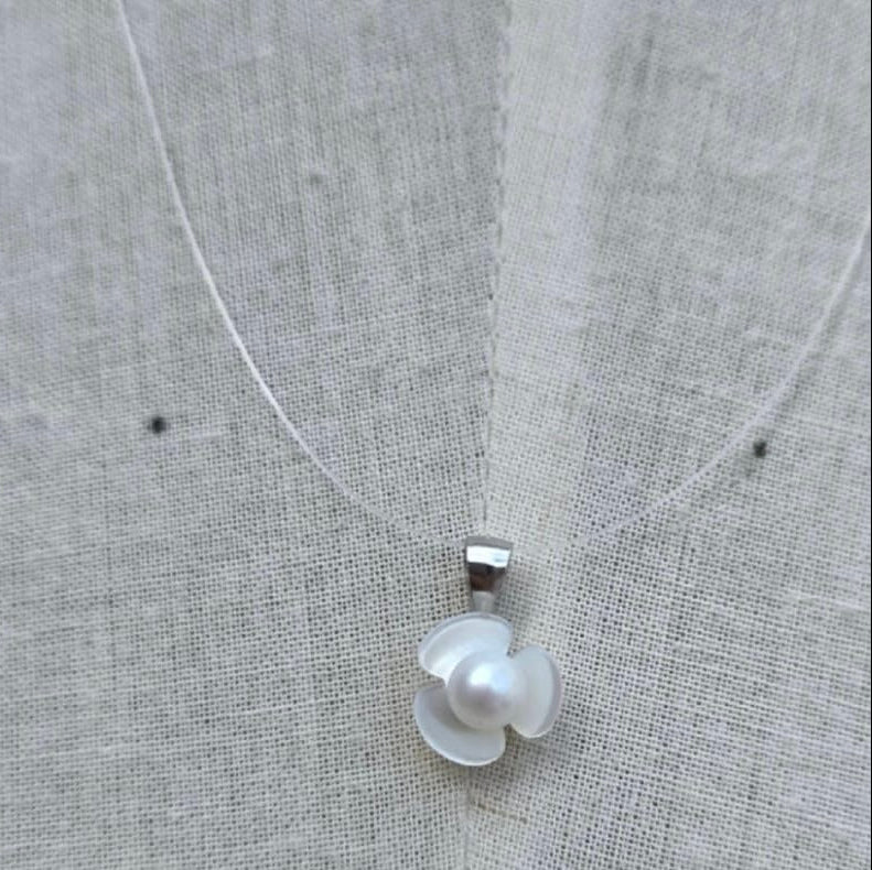 Necklace with a floral pendant on a textured fabric background