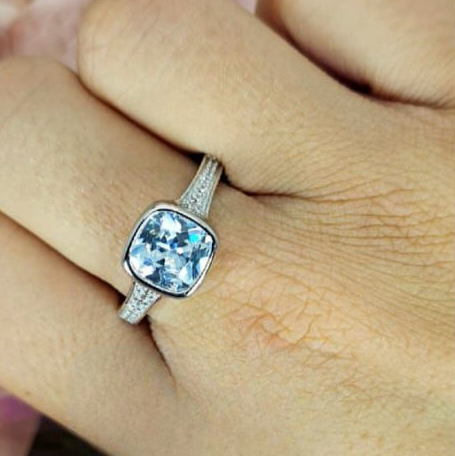 A sterling silver ring with a square cubic zirconia stone set in a tube setting, held on a person's finger.