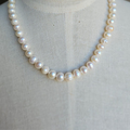 A white pearl necklace displayed on a mannequin torso.