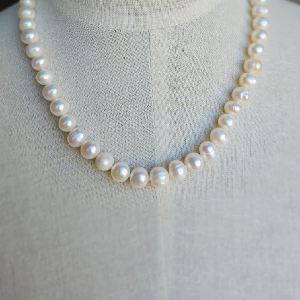 A white pearl necklace displayed on a mannequin torso.