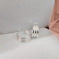 Silver ring with multiple bands on a light gray surface