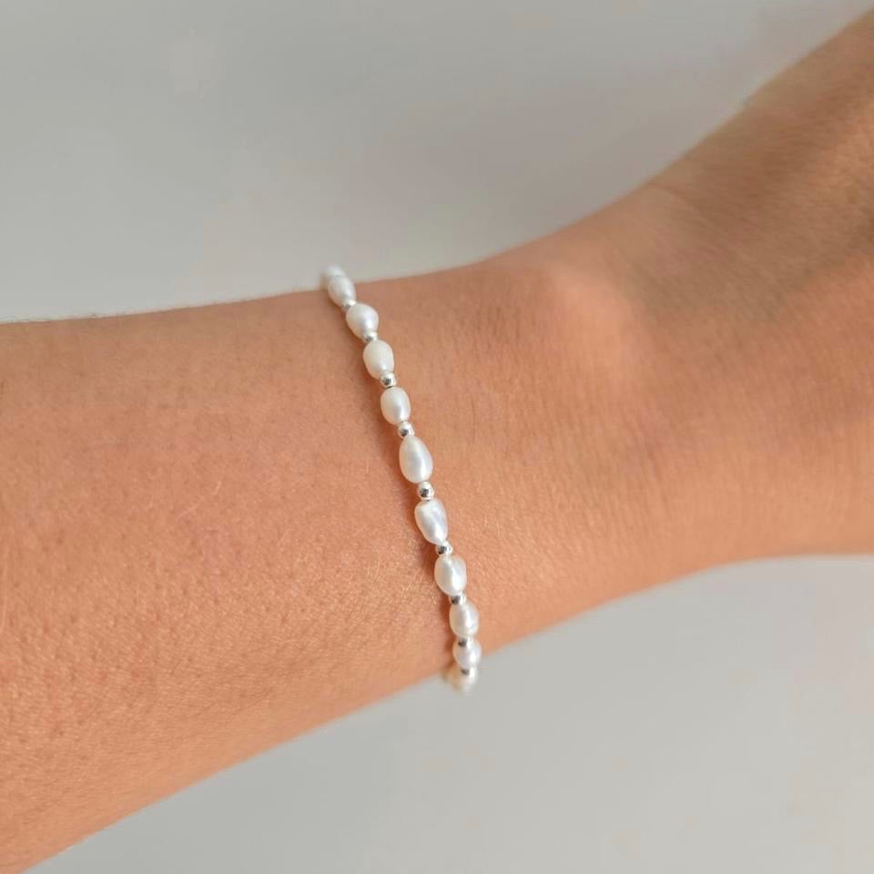 Pearl bracelet on a wrist against a neutral background