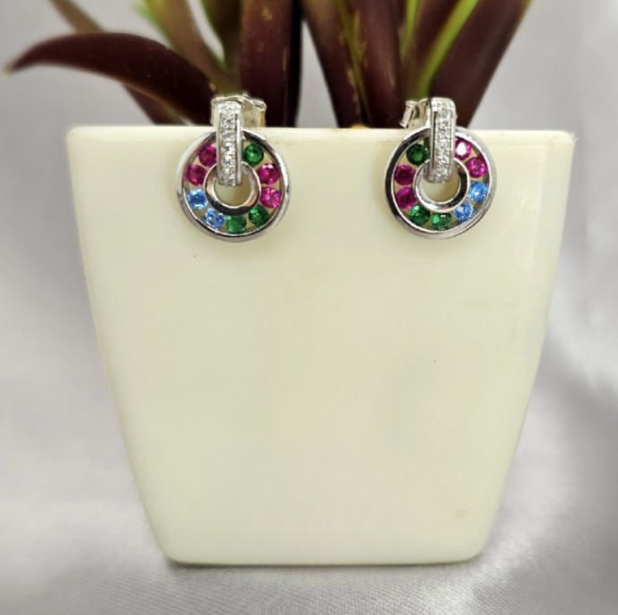 A pair of sterling silver circle drop earrings with multicolored cubic zirconia stones displayed in a white container.
