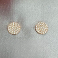 Gold round earrings with a textured design on a gray fabric background