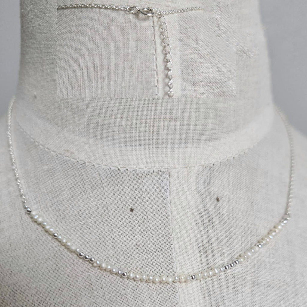 Pearl necklace on a mannequin with a plain background