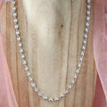 Silver chain necklace on a wooden surface with pink fabric