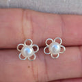 Flower-shaped pearl earrings on a hand