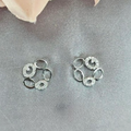 A pair of sterling silver open circle stud earrings with cubic zirconia accents, displayed against a fabric background with a floral motif.