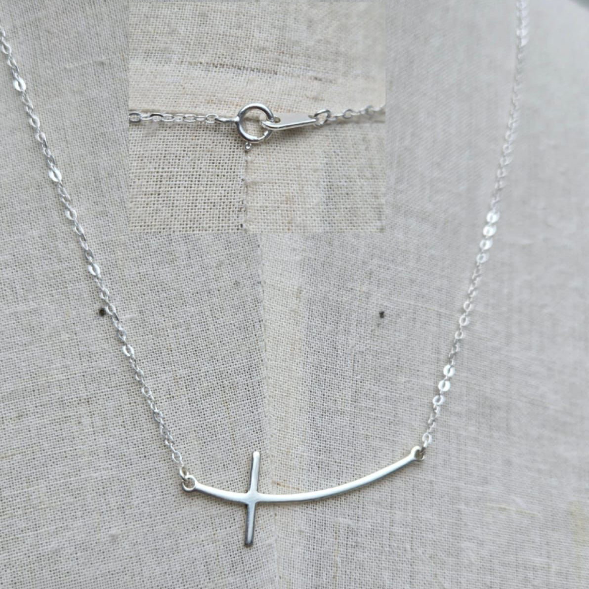 Silver necklace with a simple design on a light gray fabric background