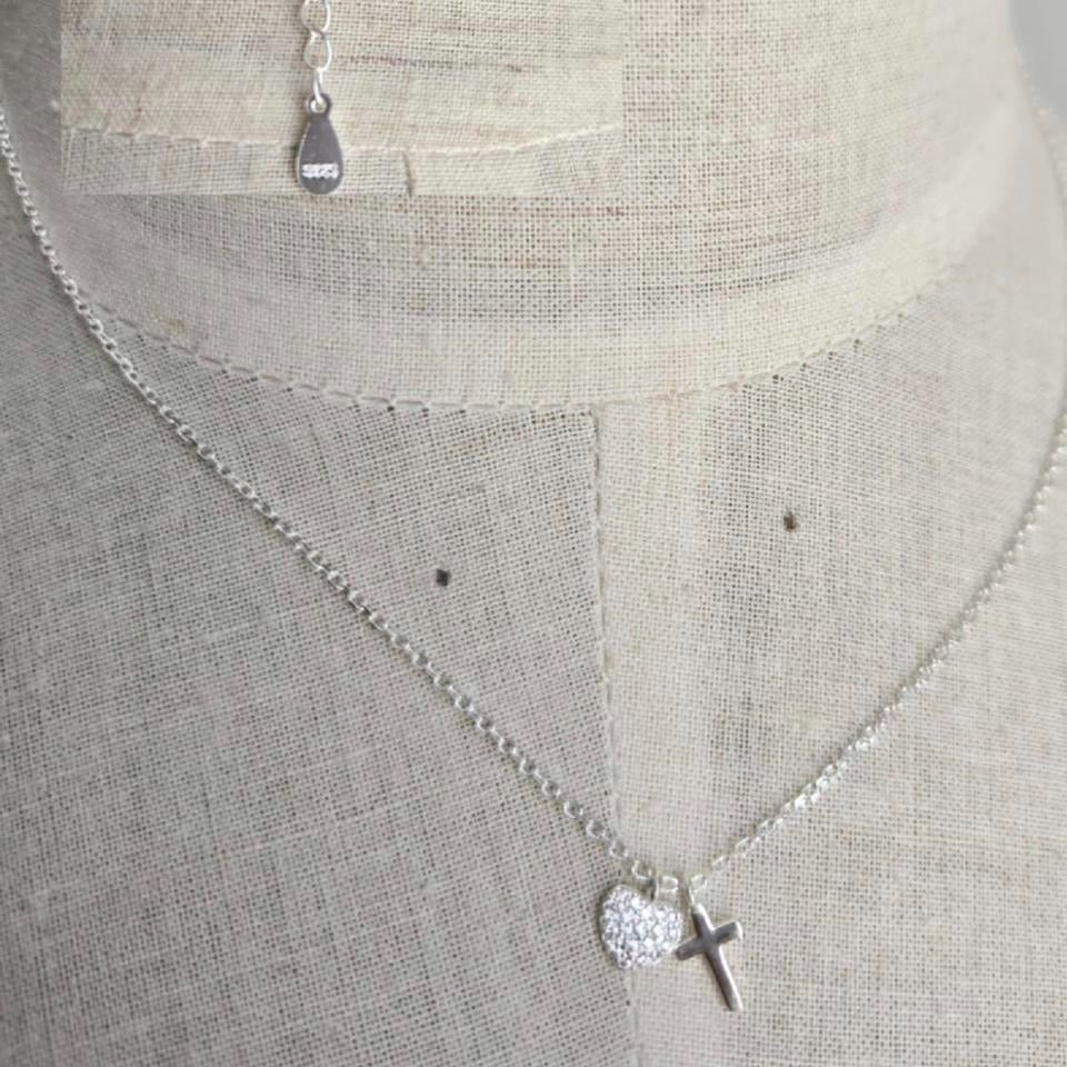 Silver necklace with a cross pendant on a mannequin.