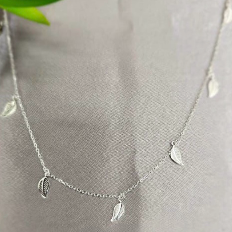 A sterling silver necklace with a design of several beautiful leaves displayed on a mannequin.