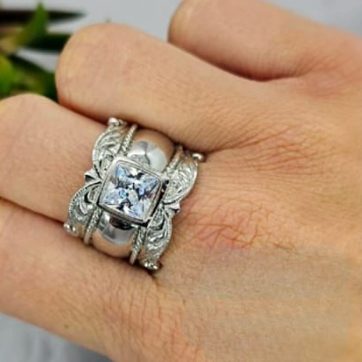 A sterling silver ring with multiple cubic zirconia stones set around its circumference, held on a person's hand.